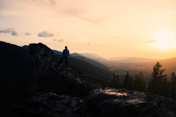 Person on mountain top at sunset, surrounded by natural landscape