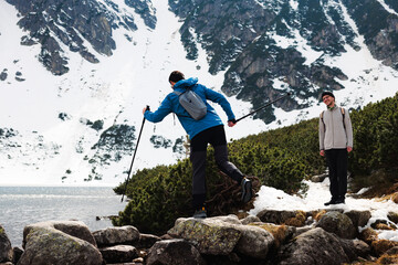 Two hikers explore snowcapped mountains and serene lake and have fun
