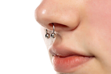 Closeup of a young serious woman's visage with piercing septum hanging from her nose