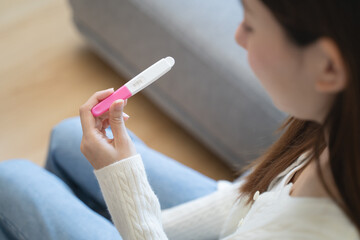 Close-up young woman checking on the pregnancy test and the result is positive.