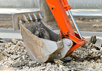 Excavator scoop and broken asphalt