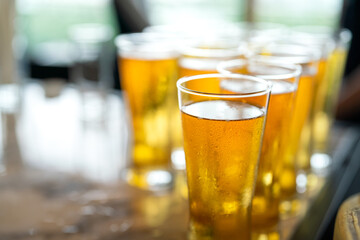 Amber lager beer in glasswares which are prepared for the party event. Refreshment drinking, close-up and selective focus. 