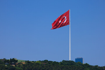 Turkish flag, on a red background white star and moon. Turkish flag flies in the wind against the backdrop of Istanbul