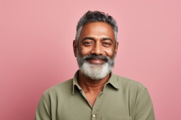 Portrait of a satisfied indian man in his 50s with arms crossed in pastel green background