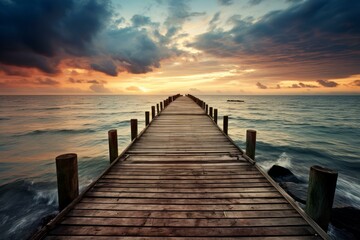 Obraz premium Wooden pier extends into a tranquil sea under a dramatic sunset sky