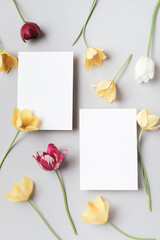 Beautiful aesthetic flowers with empty paper blank on neutral background top view. Minimal invitation or greeting card.