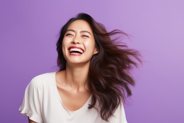 Portrait of a tender asian woman in her 40s laughing isolated on pastel purple background
