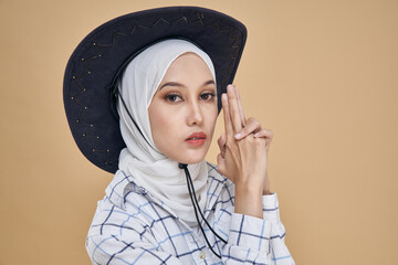 Portrait of an Asian hijab model in white shirt and blue jeans wearing cowboy hat isolated over...