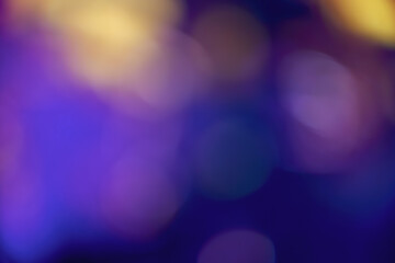 Abstract image with soft undefined shapes of blue and yellow colors and blurry circle lights like those of a music concert stage. Dark background.