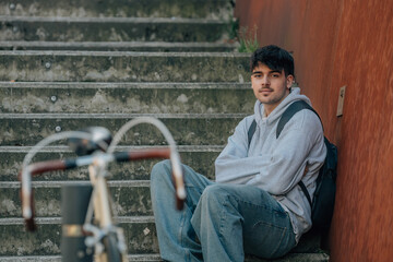 student sitting on the street with out of focus bicycle in the foreground