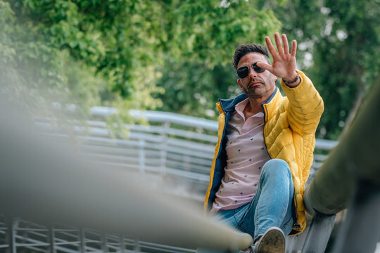 hispanic man with urban style sunglasses on the street waving