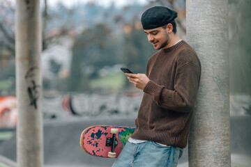 young man on the street with mobile phone and skateboard