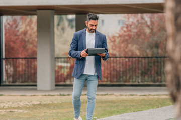attractive businessman on the street with tablet or laptop
