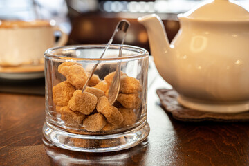 Demerara sugar, organic brown sugar cubes, teapot, cup on wooden table. Teatime organic
