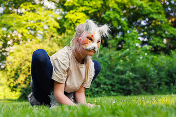 Cute young little kid girl wear cat furry mask enjoy have fun playing outdoors in forest street...
