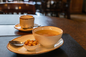 Delicious cream soup in white bowl, croutons on the table on served table in a café or restaurant, copy space close-up