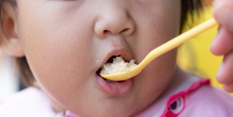 Child eating rice with a spoon close-up,Close up infant baby feeding food on the kid chair