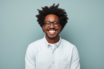 Obraz premium Portrait of a merry afro-american man in his 30s smiling at the camera while standing against pastel gray background