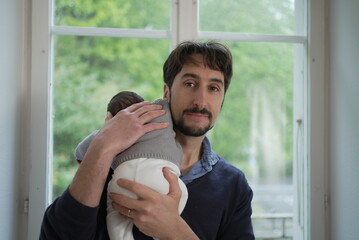 A father and his newborn share a quiet, tender moment, emphasizing the gentle bond and love between...