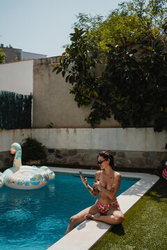 Woman at the edge of the pool with her smartphone