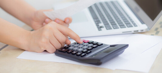 Closeup hands of woman calculating finance household with calculator on desk at home, girl checking bill for saving and planning expenses, debt and loan, tax and accounting, business and financial.