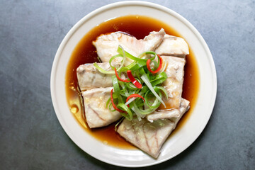 Sea bass fillet steam with soy sauce. Top view on black table background.