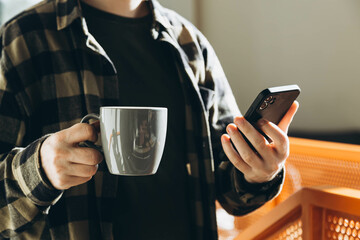 A man uses a smartphone and drinks coffee in the morning in the office.