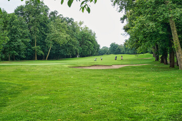 panorama con green di campo di golf giocatori prato verde e alberi in prospettiva