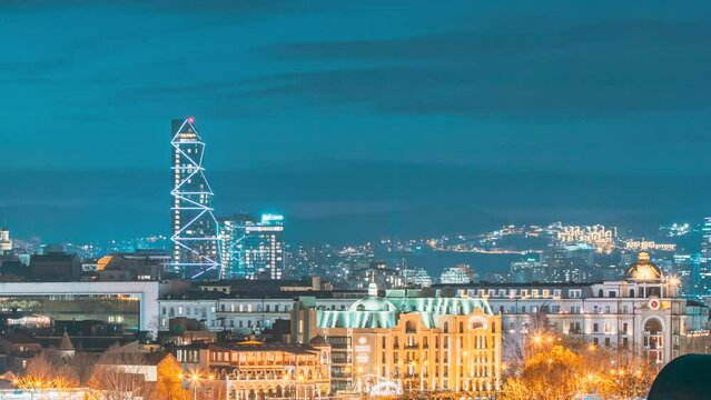 Tbilisi, Georgia. Nightlife Of City. 4k Hyperlapse High Tower Skyscraper Building On Background Of Urban Cityscape During Blue Hour Evening Night Illumination Lights. Tbilisi Skyline. Radisson Blu