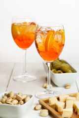 Happy hour with Aperol Spritz served with an orange slice in wine glasses. White wooden table, high key, high resolution