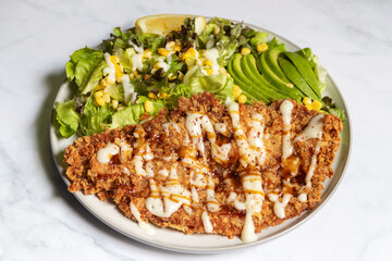 Delicious and healthy salad with deep fried fish, avocado, corn and a tangy dressing.