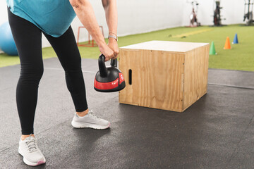 View of a part of a woman's body lifting a kettlebell in the gym.
