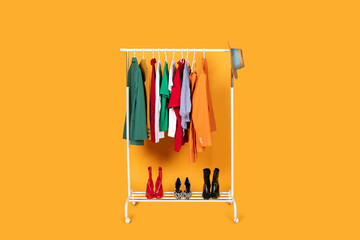 A rack filled with various clothing items is displayed against a vibrant yellow background. The...