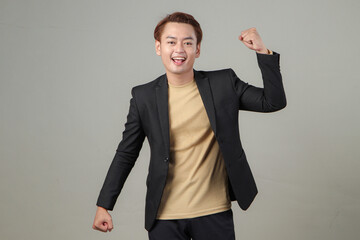 portrait of happy asian businessman wearing suit with clenched fist celebration in winning, success...