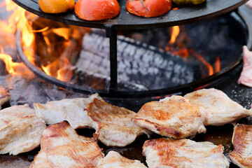 Raw fresh pieces of meat are placed on a cast iron grill to be grilled.