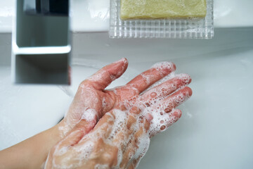 The process of washing hands with natural soap over the sink.