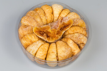 Dried figs in round plastic packaging on a gray background