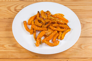 Baked slices of butternut squash on dish on rustic table