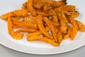 Baked slices of butternut squash on dish, fragment close-up