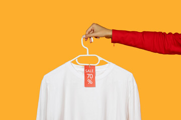 Woman hand emerging from a red sleeve, holding a white hanger with a crisp white shirt on it. A red...