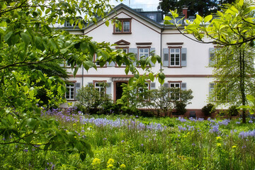 Trees in front of white building in the Hermannshof Gardens in Weinheim, Germany.