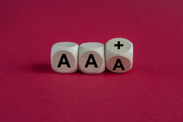 Turned a wooden cube and changes the expression AAA to AA plus. Beautiful red background. Symbol...