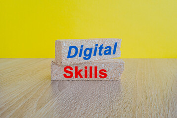 Digital skills symbol. Brick blocks with red words digital skills. Beautiful yellow background, wooden table. Business concept. Education and work.