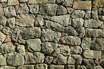Background, texture of a wall made of natural stone of gray color, the stones are selected and well adjusted to each other