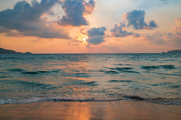 sunset over sea and sun rays in clouds, sandy beach, Thailand