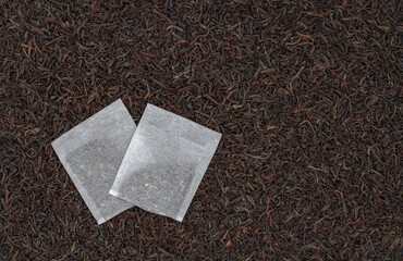 two tea bags on a background of black tea