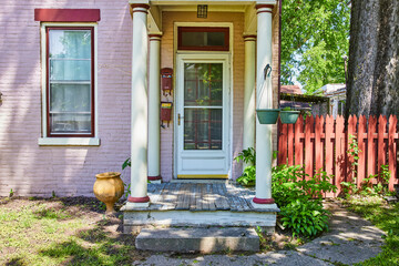 Charming Pink Brick House with Weathered Porch and Lush Greenery