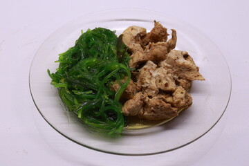 Braised chicken breast with chukka salad on a transparent plate.