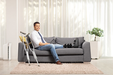Man with a foot injury and leg brace sitting on a sofa