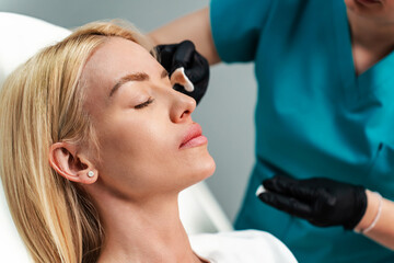 Beautiful blonde woman patient preparing for medical and beauty treatment with botulinum toxin...
